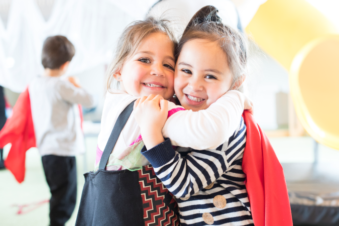 Two young tamariki embracing, smiling at the camera.