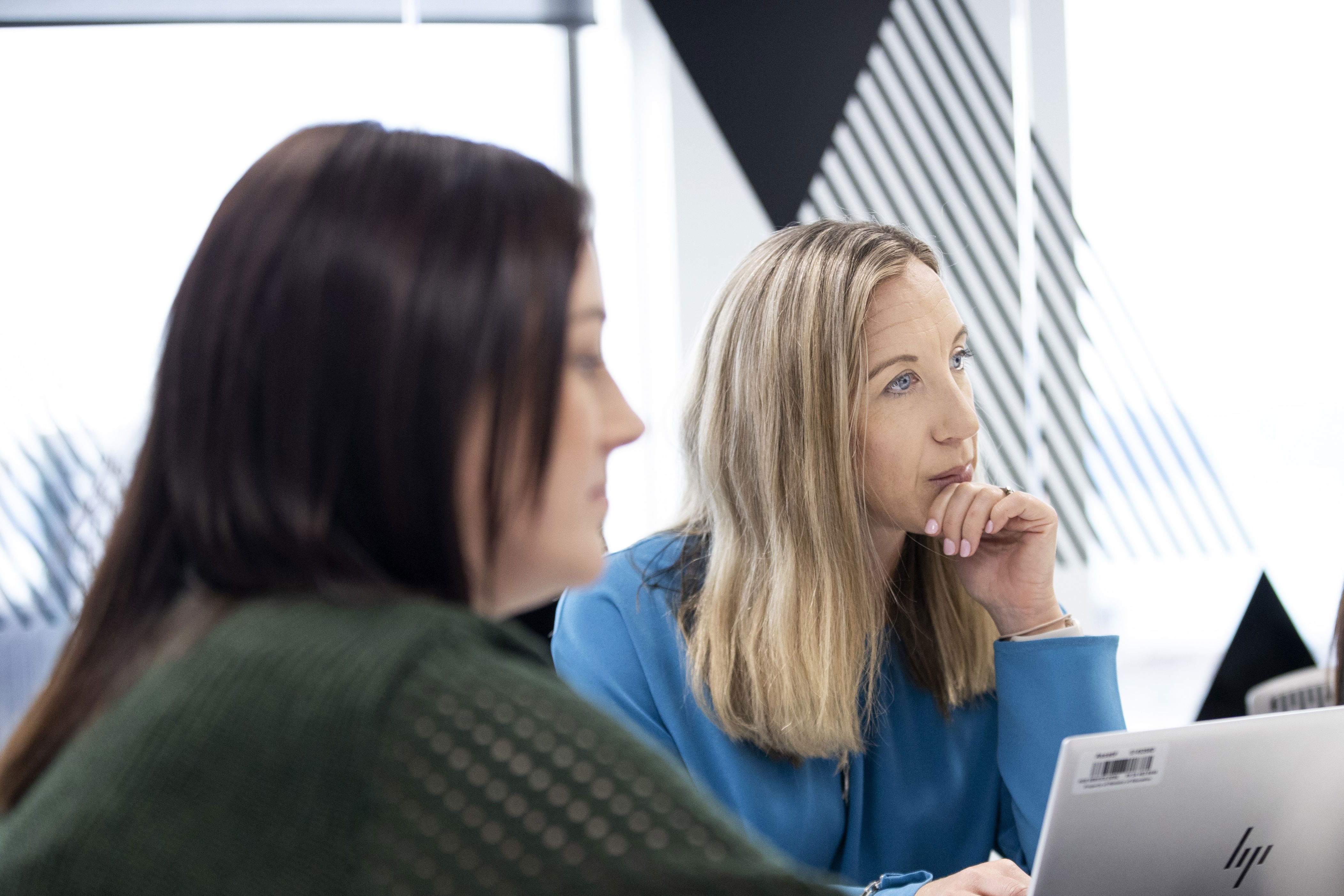 People in a meeting room, with one working on a laptop. 