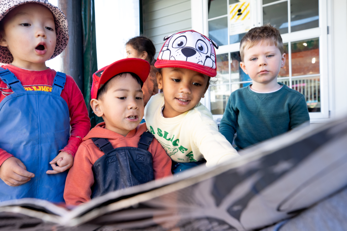 A group of children enthusiastically reading a book.