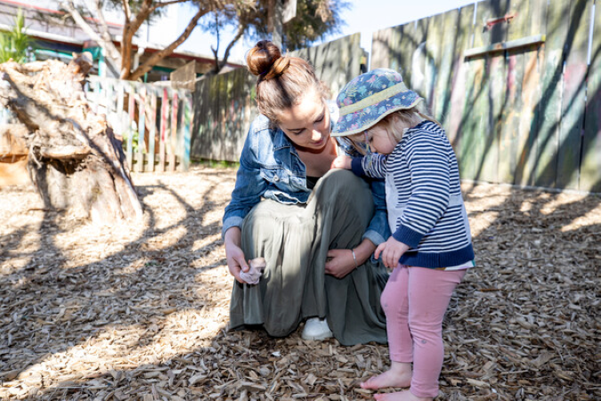 Adult and child outside looking at child’s feet