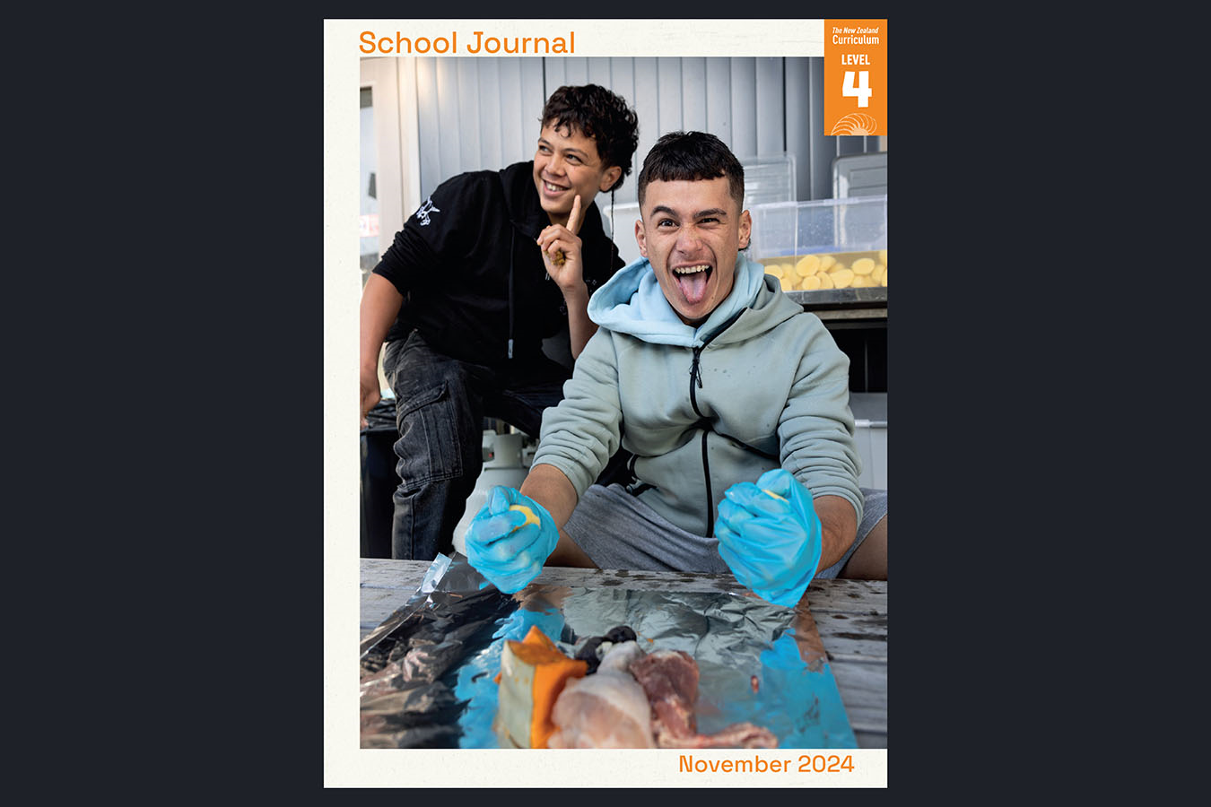 Book cover for School Journal Level 4 November 2024. Cover shows a photo of two boys enjoying the preparation of a hāngī.