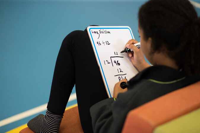 Student working on a maths equation on a whiteboard