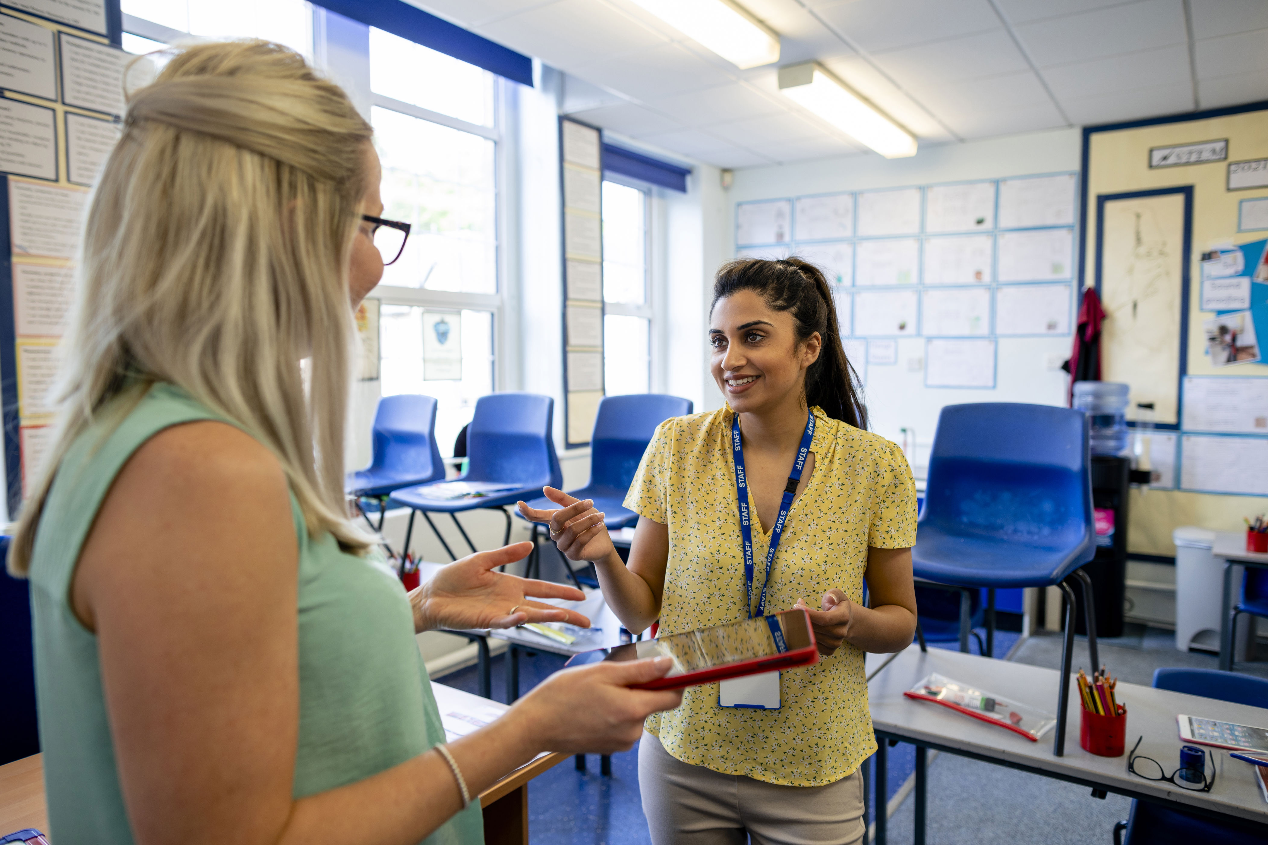 Two teachers speaking in a classroom. 