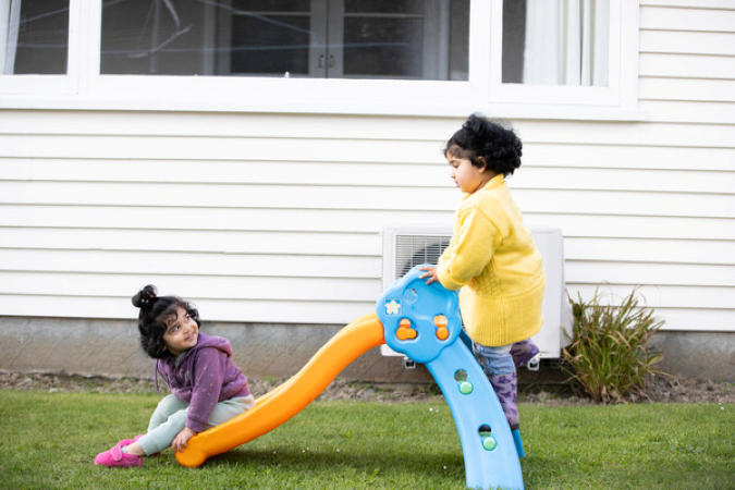 Two children playing on a slide outside