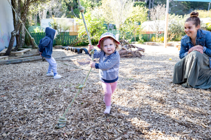 Adult and two children playing outside with a rope swing