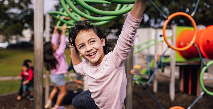 A child swinging on climbing equipment in a school playground