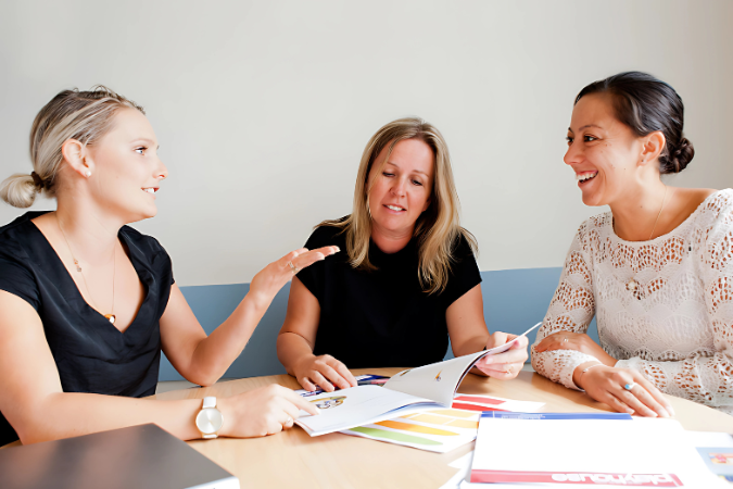 Three teachers working at a desk.