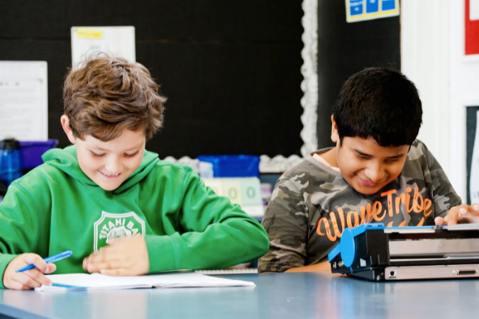 Two students working at a desk.