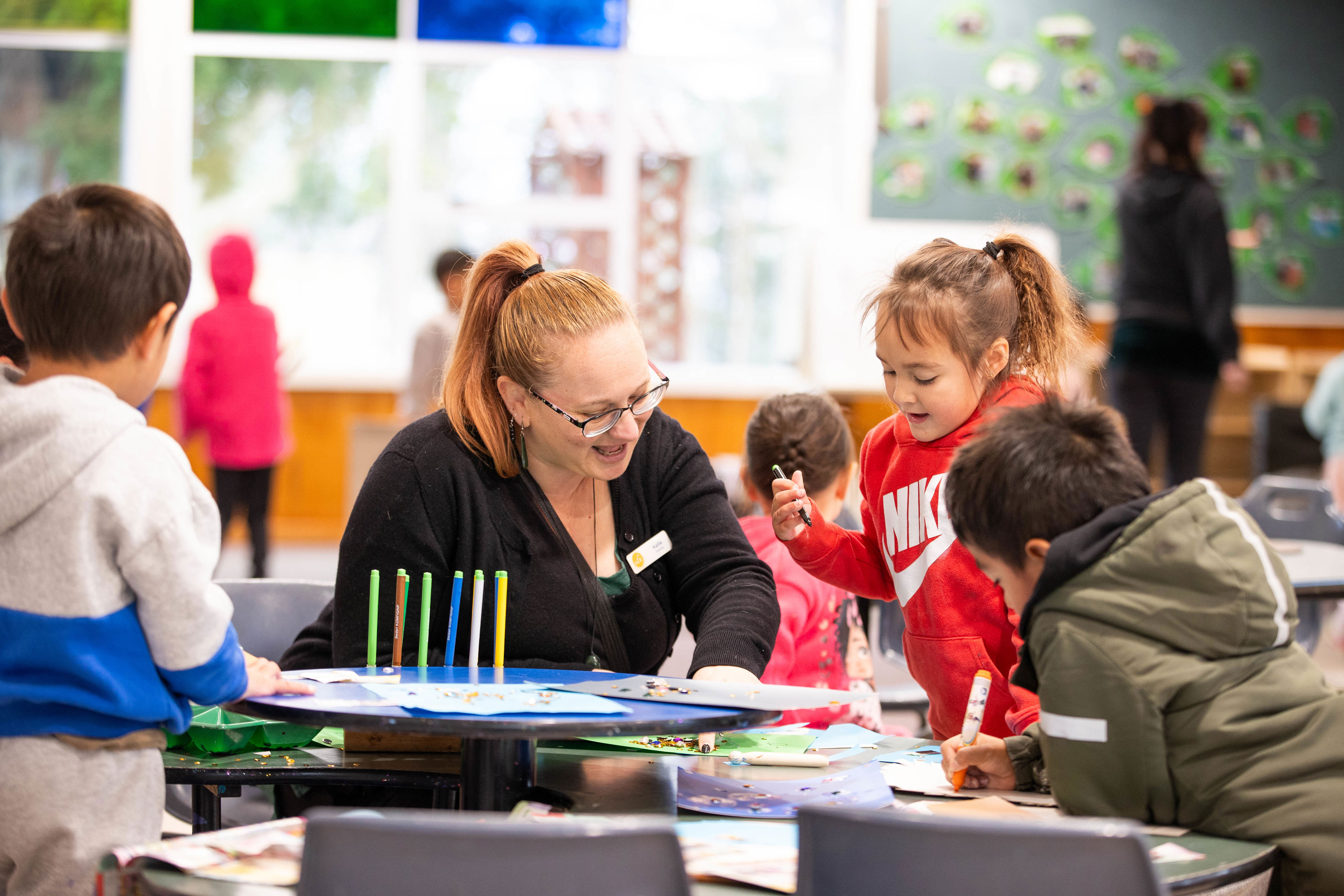 Teacher working alongside children at a table.