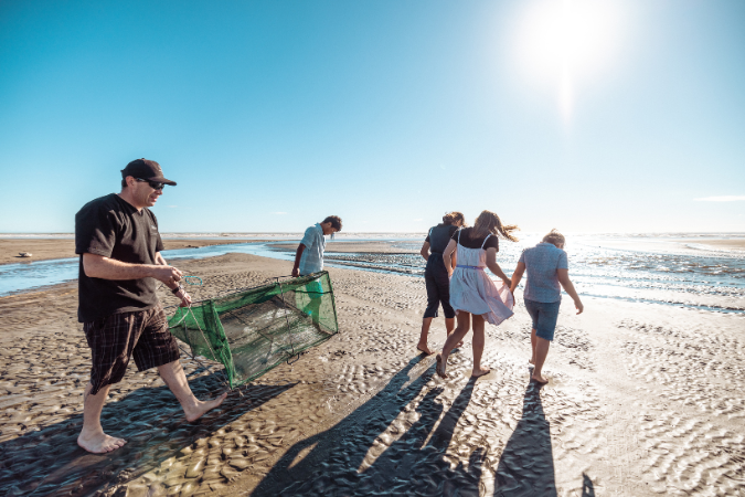 teacher and a group of students on a beach with a net cage
