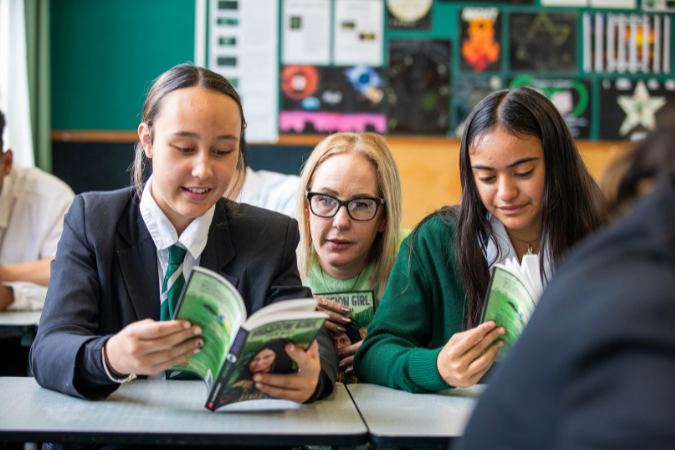teacher behind students while they read novels