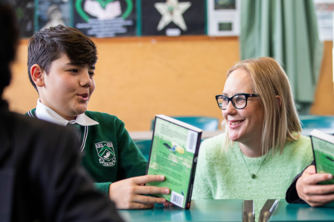one student reading novel with teacher
