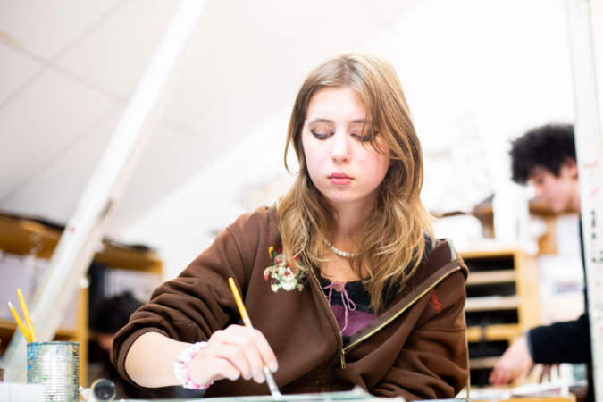 student looking down while painting a piece of art